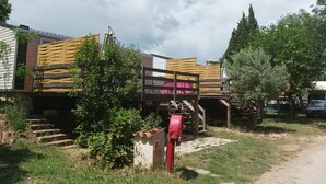 Una cabaña rústica con un porche de madera, una pequeña escalera que lleva a la entrada y un buzón.