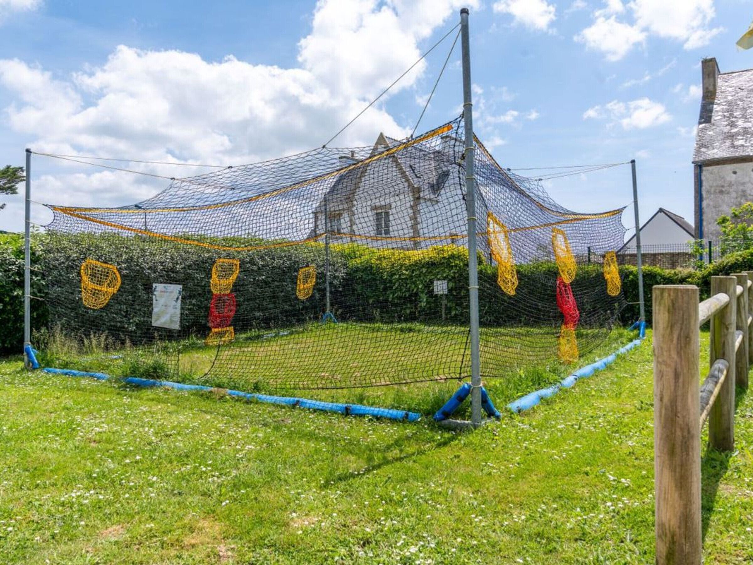 A sports netting structure in an outdoor setting with a building in the background.