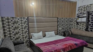 Une chambre à coucher comprenant un lit, deux fauteuils, un mur recouvert de panneaux en bois et un mur carrelé.