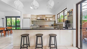 Une cuisine moderne dotée d’un îlot central, de tabourets de bar et d’un coin repas avec une table et des chaises.