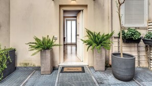 A welcoming entrance with a 'Welcome' mat, potted plants, and a door leading to a hallway. - Sabina 2 -bedroom apartment with kitchen in center Roma (Roma)
