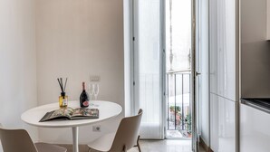 A modern kitchen with a white countertop, a dining area with a round table, and a sliding glass door leading to a balcony. - Sabina 2 -bedroom apartment with kitchen in center Roma (Roma)