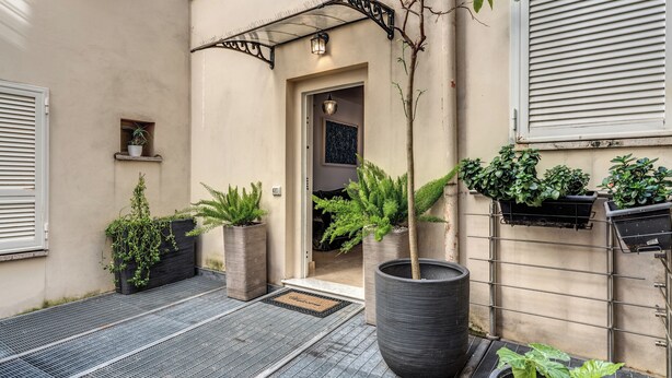 A hotel entrance with a metal ramp, potted plants, and a door leading inside. - Sabina 2 -bedroom apartment with kitchen in center Roma (Roma)