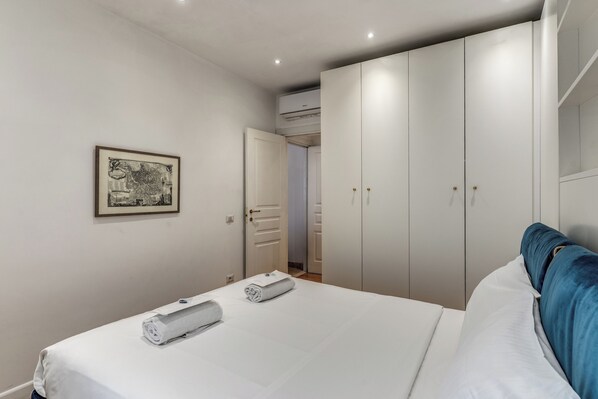 A bedroom with a bed, white linens, a blue headboard, a wardrobe, and a framed picture on the wall. - Sabina 2 -bedroom apartment with kitchen in center Roma (Roma)