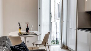 A modern living room with a round white table, a sofa, and a balcony with a view of buildings. - Sabina 2 -bedroom apartment with kitchen in center Roma (Roma)
