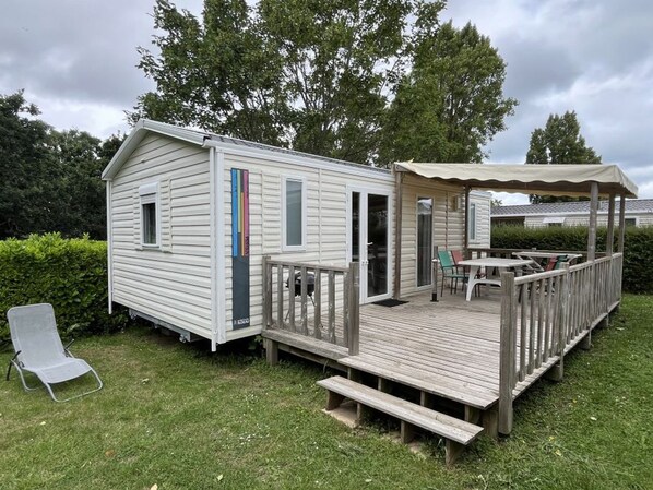 A small, single-story cabin with a deck and a covered patio area. - Mobile home with terrace in Binic for 4 people (Binic)