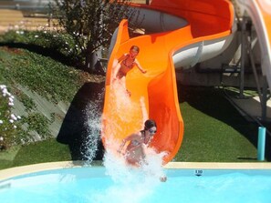 A water slide at a poolside area with a clear view of the pool and surrounding greenery. - Mobile home with terrace in Binic for 4 people (Binic)