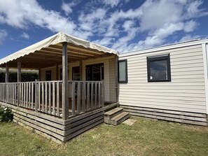 A mobile home with a porch, a covered deck, and a small window.
