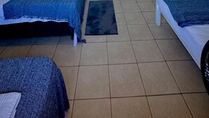 Una habitación con dos camas, un armario de madera y suelo de baldosas.