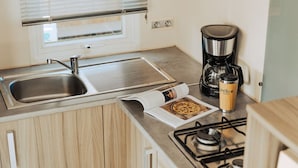 A kitchen with a stainless steel sink, a coffee maker, and a stove. - Mobile home with terrace in Saint-Jean-de-Monts (Saint-Jean-de-Monts)