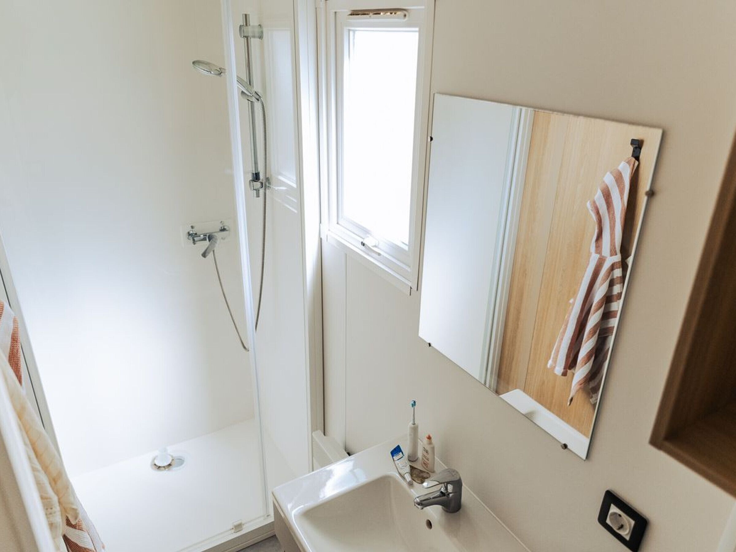 Un baño con ducha, lavabo y espejo.