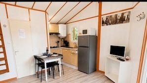 Eine kleine Küche mit Esstisch, Stühlen, einem Kühlschrank, einer Mikrowelle und einem Fernseher.