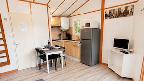Eine kompakte Küche mit Esstisch, Kühlschrank und Fernseher auf einem Schrank.