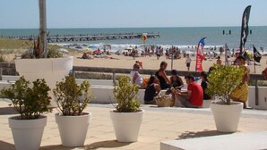 A beachside patio with potted plants, a wooden deck, and a view of the beach and ocean. - Mobile home in Saint-Jean-de-Monts with terrace (Saint-Jean-de-Monts)