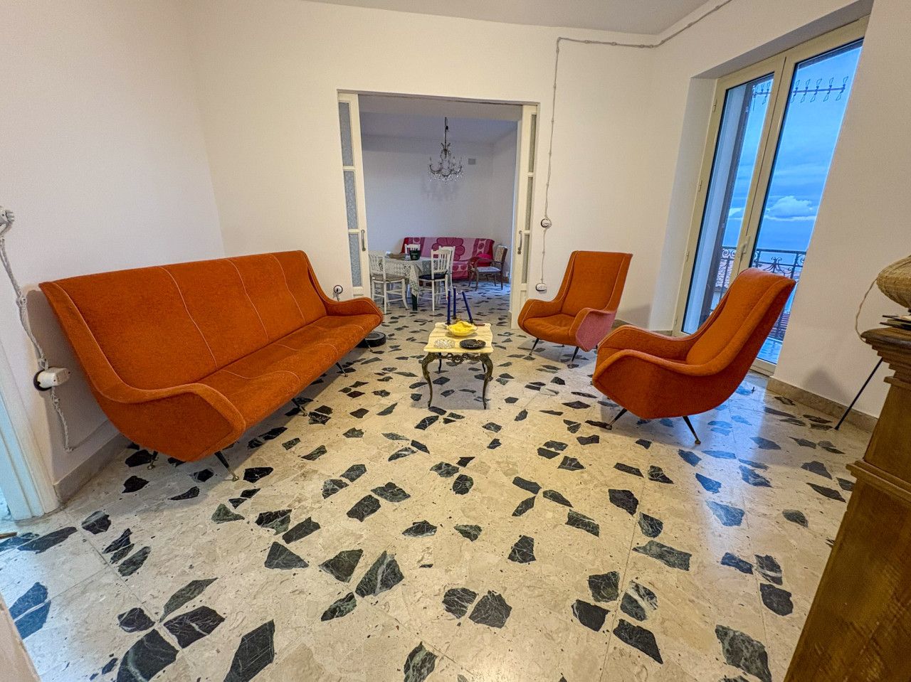 Una habitación con piso estampado, sofás anaranjados y una mesa con sillas.