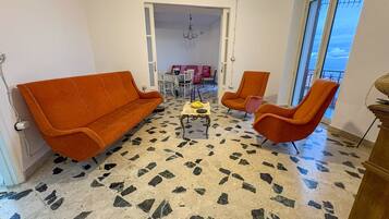 Una habitación con piso estampado, sofás anaranjados y una mesa con sillas.