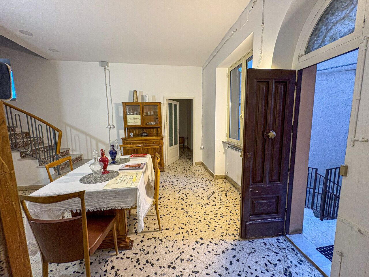 Ein Essbereich mit Tisch für zwei Personen, einer Holzkommode und einer Treppe zu einer weiteren Ebene.