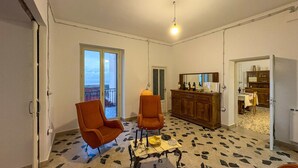 A room with two orange armchairs, a wooden cabinet, and a dining area with a table and chairs. - B&B StudioArcodia - Camera Matrimoniale (San Marco D`alunzio)