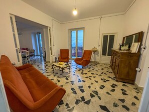 A living room with two orange armchairs, a small table, and a wooden cabinet. The floor has a patterned tile design. - B&B StudioArcodia - Camera Matrimoniale (San Marco D`alunzio)