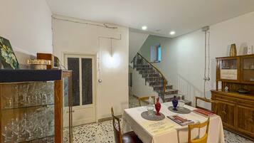 Un coin repas avec une table dressée pour quatre personnes, un escalier en arrière-plan et un buffet en bois contenant de la verrerie.
