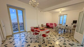 A dining area with a red table and chairs, a chandelier, and a view through a glass door. - B&B StudioArcodia - Camera Matrimoniale (San Marco D`alunzio)