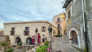 A narrow street with buildings featuring arched doorways and windows, stone steps, and potted plants. - B&B StudioArcodia - Camera con Balcone (San Marco D`alunzio)