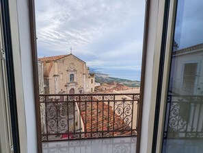 A balcony with wrought iron railings overlooking a historic building with a cross on top, set against a cloudy sky. - B&B StudioArcodia - Camera con Balcone (San Marco D`alunzio)