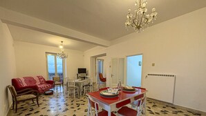 A dining area with a red table and chairs, a chandelier, and a patterned floor. - B&B StudioArcodia - Camera con Balcone (San Marco D`alunzio)