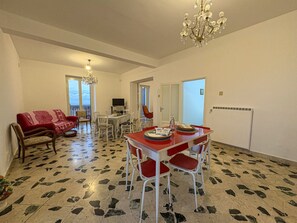A dining area with a red table and chairs, a chandelier, and a patterned floor. - B&B StudioArcodia - Camera con Balcone (San Marco D`alunzio)