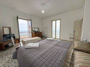Un dormitorio con una cama grande, un aparador, un televisor y un balcón con vistas.