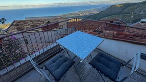 Una terraza con mesa y sillas, con vistas a un paisaje costero.