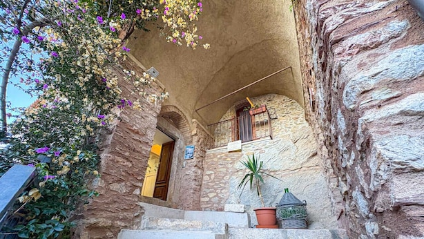 Una escalera de piedra que conduce a una puerta de madera, con un balcón arriba.