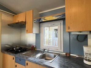 A compact kitchen with a sink, stove, and wooden cabinets. - Mobile home with terrace in Villecroze (Villecroze)