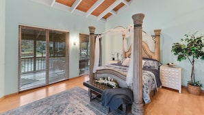 A four-poster bed with a canopy, a bench, and a nightstand with a plant.