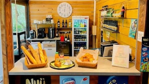 A café counter with a clock, coffee machine, and shelves of beverages. - Cozy chalet with terrace for 4 guests (Camon)