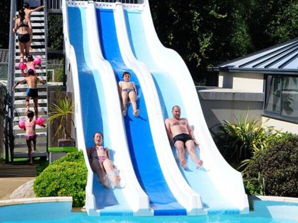 A water slide with multiple lanes, a pool, and a building in the background.