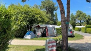 Een camping met tenten en een geparkeerde auto in de buurt.