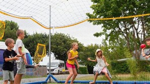 Een groep mensen speelt een balspel in een omheind buitengebied.
