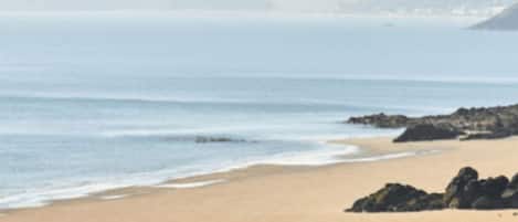 Una playa con una vista despejada del océano y colinas a lo lejos.