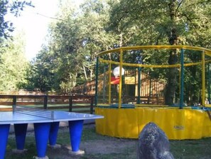 Ein Tischtennistisch mit blauen Beinen, umgeben von einer gelb-grünen Spielkonstruktion mit Netz.