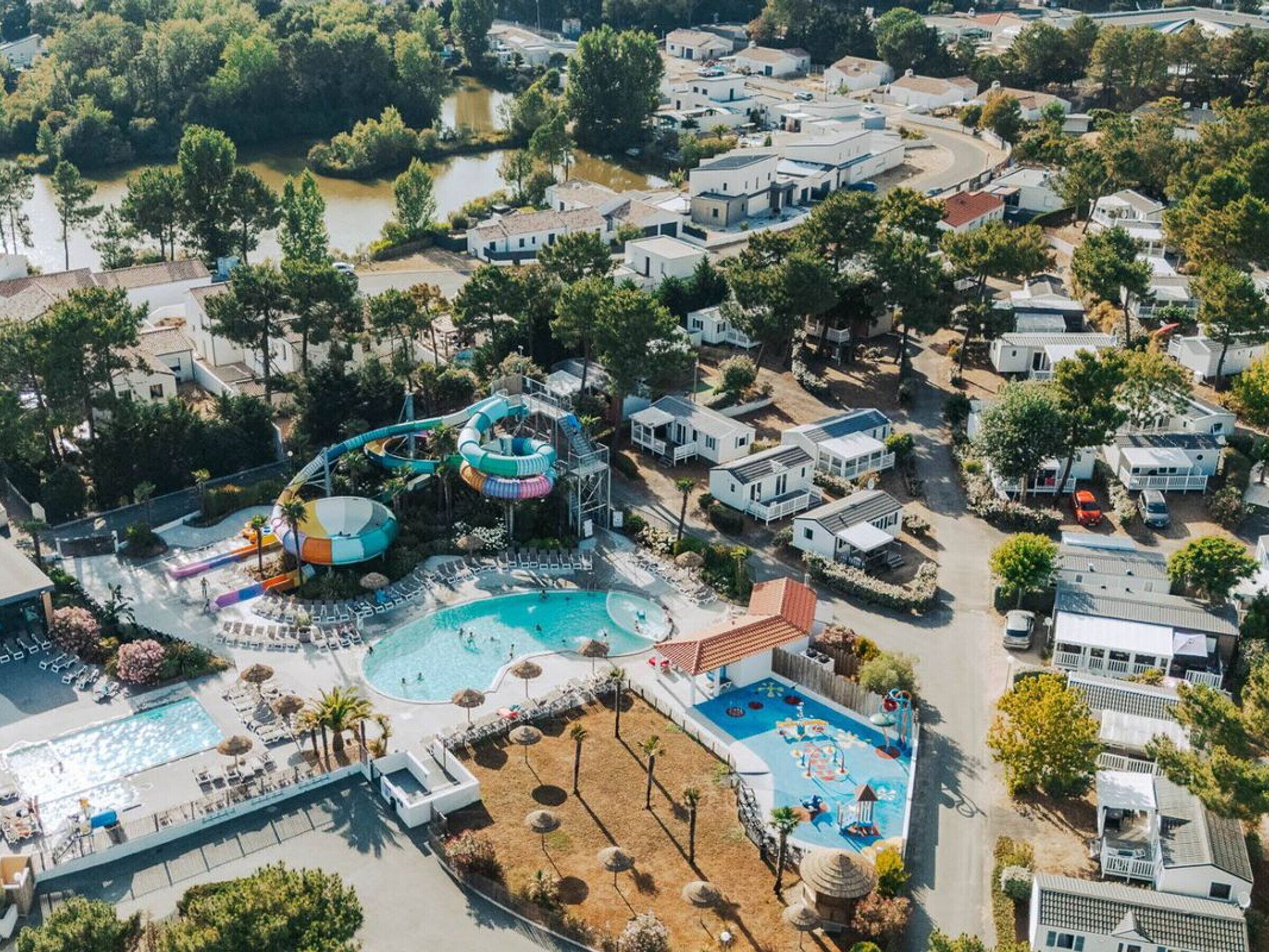 Vue aérienne d’un complexe hôtelier doté d’un parc aquatique, de plusieurs piscines et de logements mobiles.
