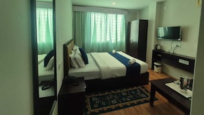Ein Hotelzimmer mit Bett, Fernseher, Schreibtisch und Spiegel.
