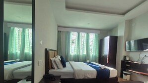 Ein Hotelzimmer mit Bett, Fernseher, Kleiderschrank und Schreibtisch mit Stuhl.