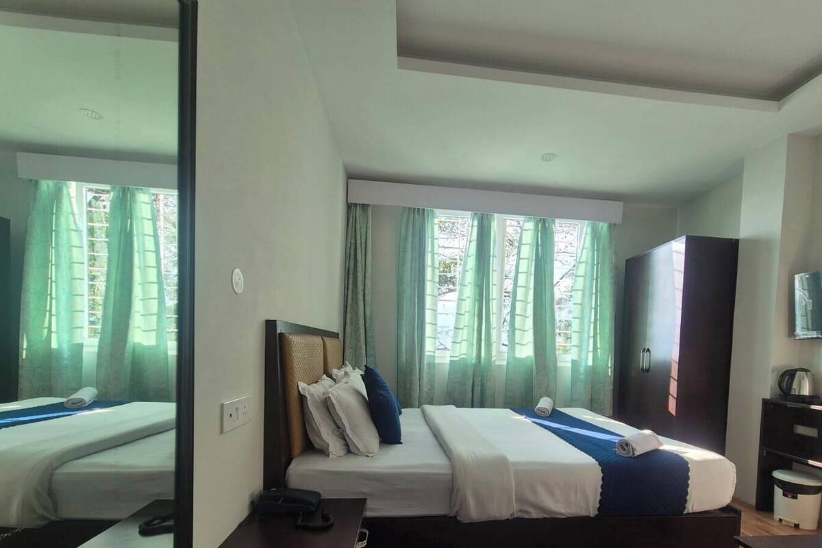 A hotel room with a bed, a TV, a wardrobe, and a desk with a chair.