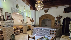 A spacious lobby with a high ceiling, ornate chandeliers, a central seating area with a patterned sofa, and a decorative fireplace. - RIAD RAHBA FEZ (Fes)