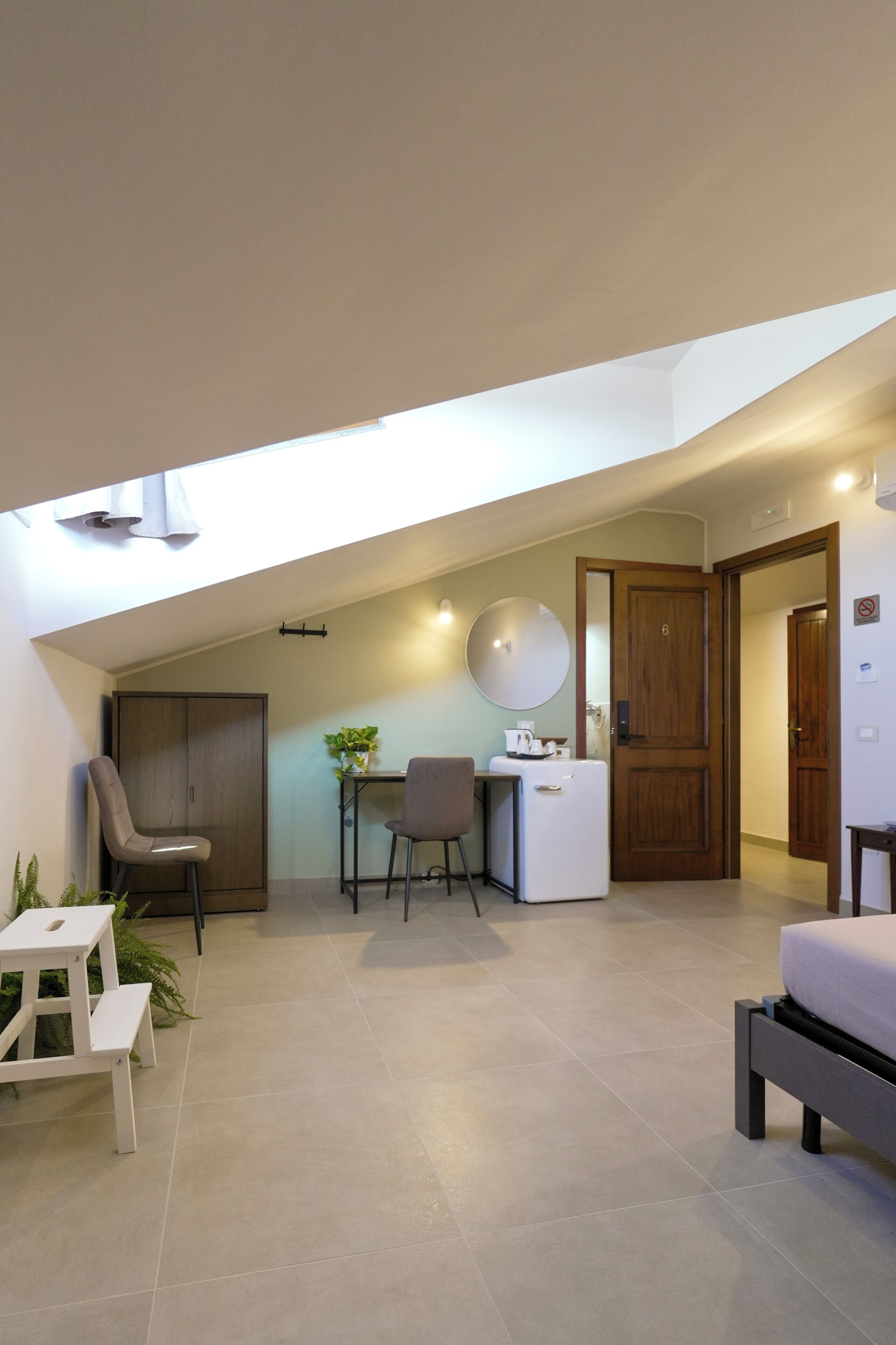 A modern room with a skylight, a desk, a chair, a bed, and a wardrobe.