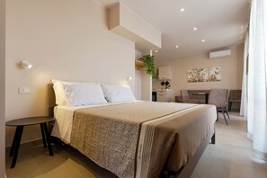 Habitación de hotel moderna con una cama grande, una mesita, una silla, un escritorio y una planta.