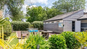 A garden with a wooden building, a blue water feature, and a map sign. - Mobile home 30m² with terrace in Tréguennec for 6 people (Tréguennec)