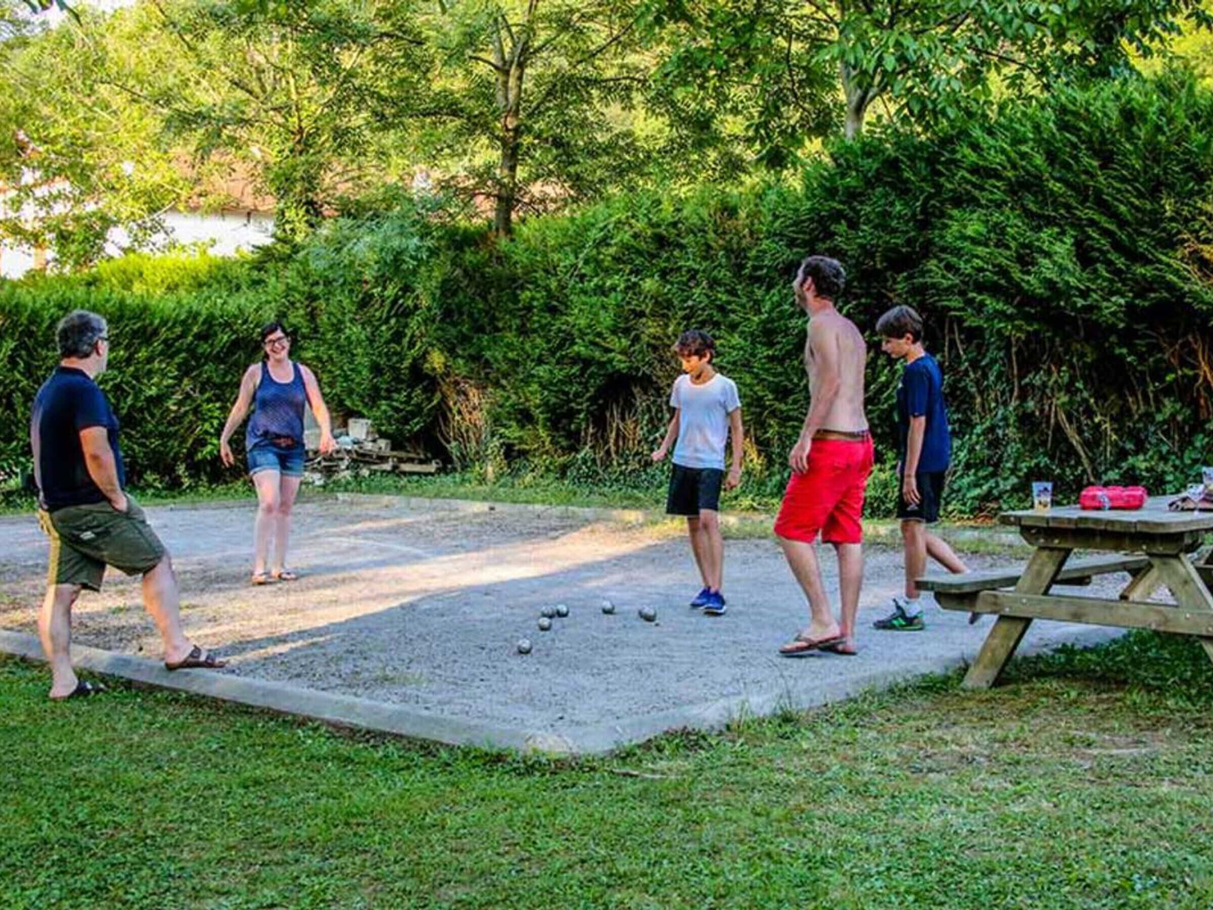En grupp människor spelar krokett utomhus, och i närheten står ett picknickbord.