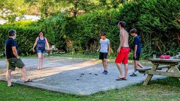En grupp människor spelar krokett utomhus, och i närheten står ett picknickbord.